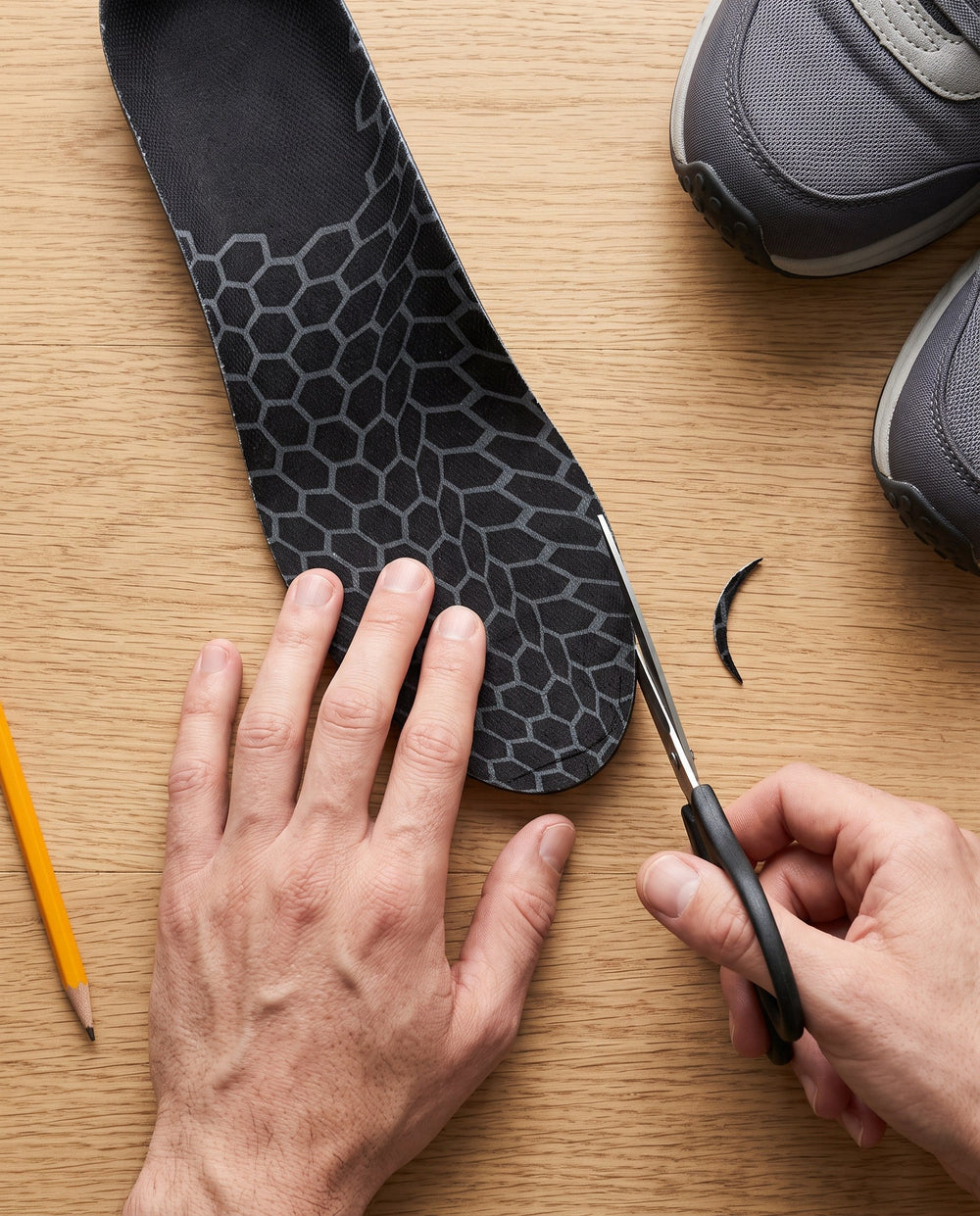Hands trimming the toe of an insole with scissors