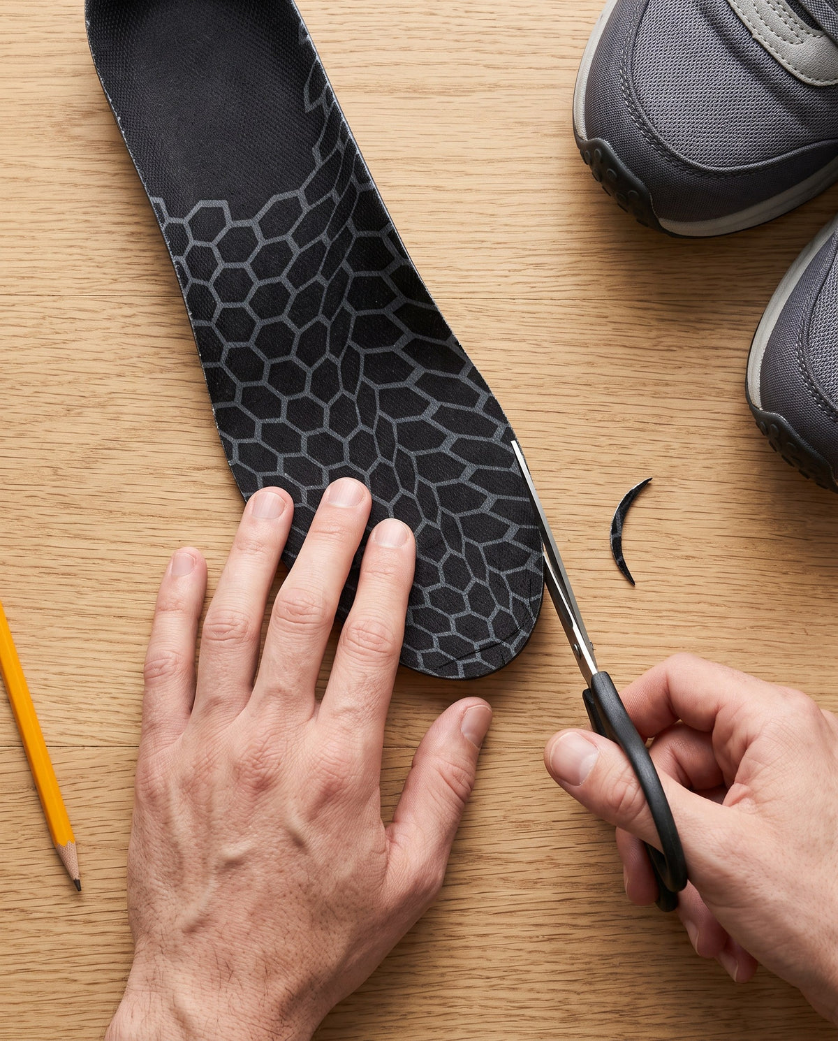 Hands trimming the toe of an insole with scissors
