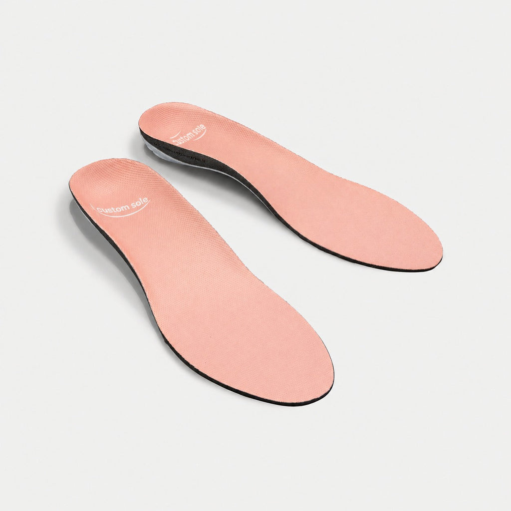 Apricot custom insoles shown at an angle to reveal the contoured arch and deep heel cup