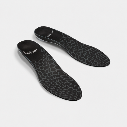 Carbon Cell custom insoles shown at an angle to reveal the contoured arch and deep heel cup: black knit cover with a grey hexagonal cell pattern and CustomSole logo at the heel